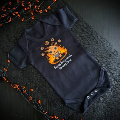 Black goth baby vest with cute demon goat design and the slogan “Barely Summoned, Already Tired”, alternative goth baby grow for spooky parents