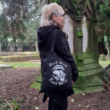 black goth tote bag with goth girls taste better tongue eye design worn in atmospheric graveyard setting