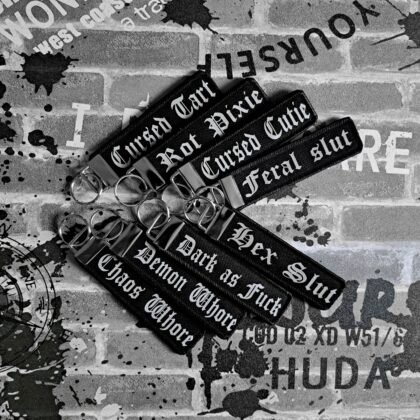 Collection of gothic slogan keyrings including cursed cutie, hex slut, rot pixie and dark humour goth keychains.
