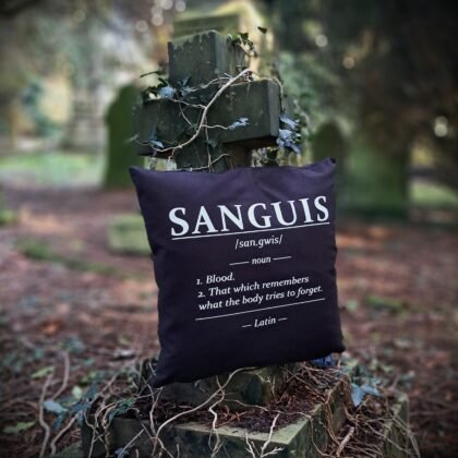 Sanguis gothic cushion cover with Latin dictionary style blood definition printed in white on black Fairtrade cotton displayed on an ivy covered grave cross.
