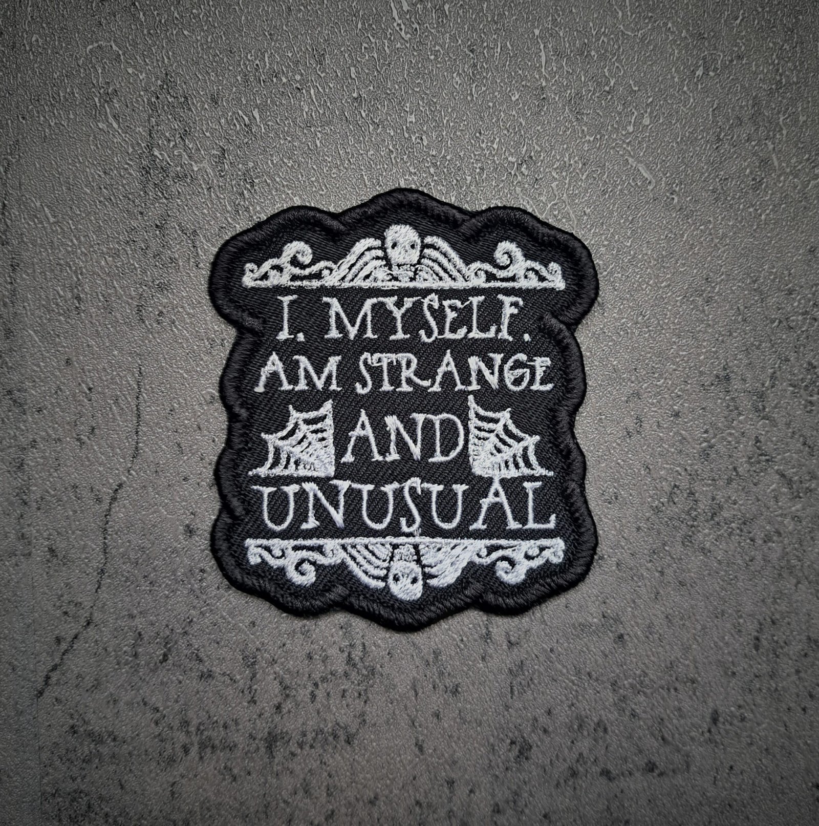 Strange and Unusual gothic embroidered patch with skull and cobweb design in black and white