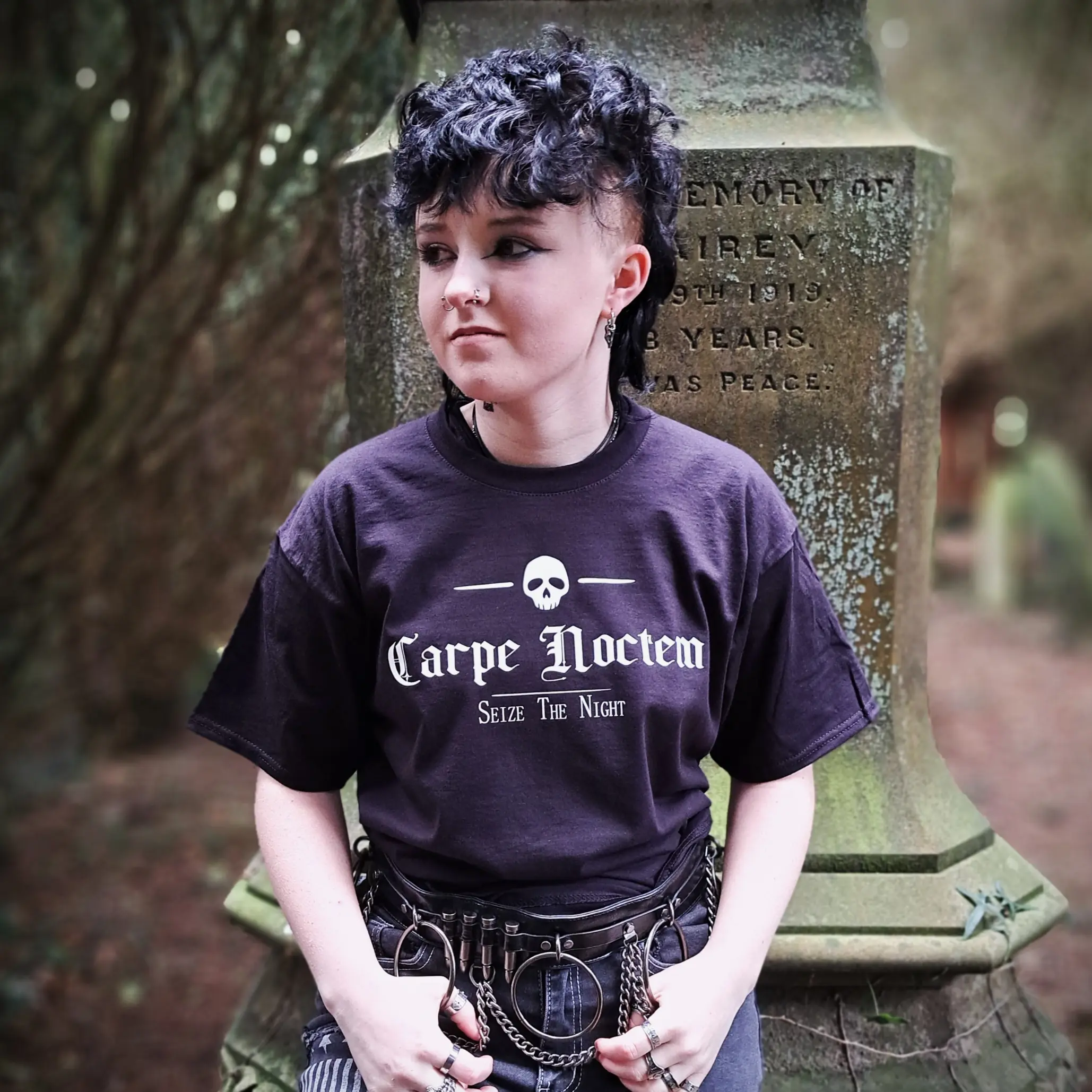Carpe Noctem gothic t-shirt in black with white skull and Seize the Night lettering, modelled in front of a weathered gravestone.